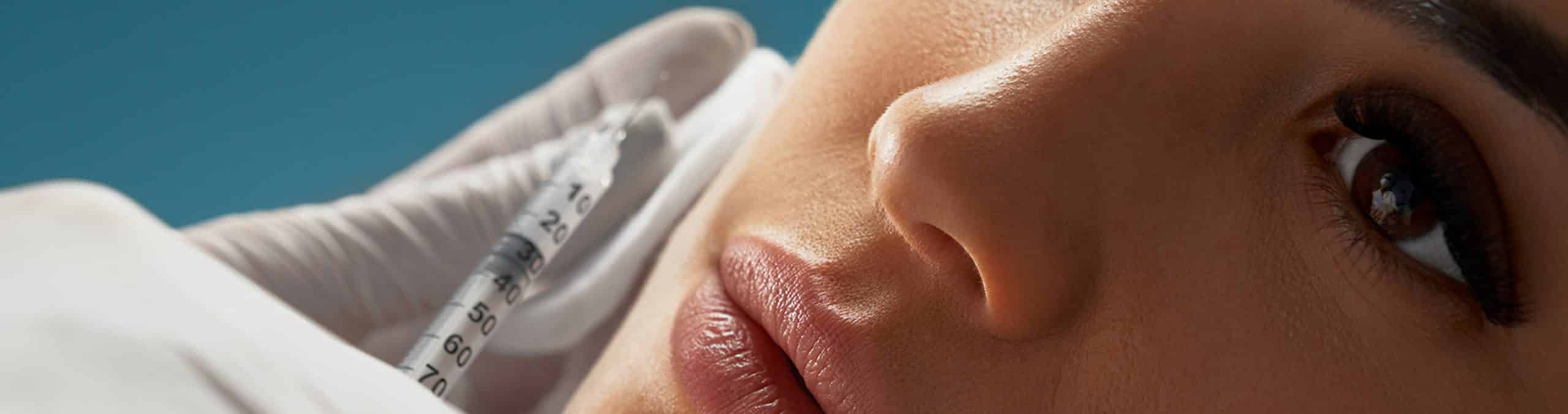 Cosmetologist using syringe correct female face 1 1