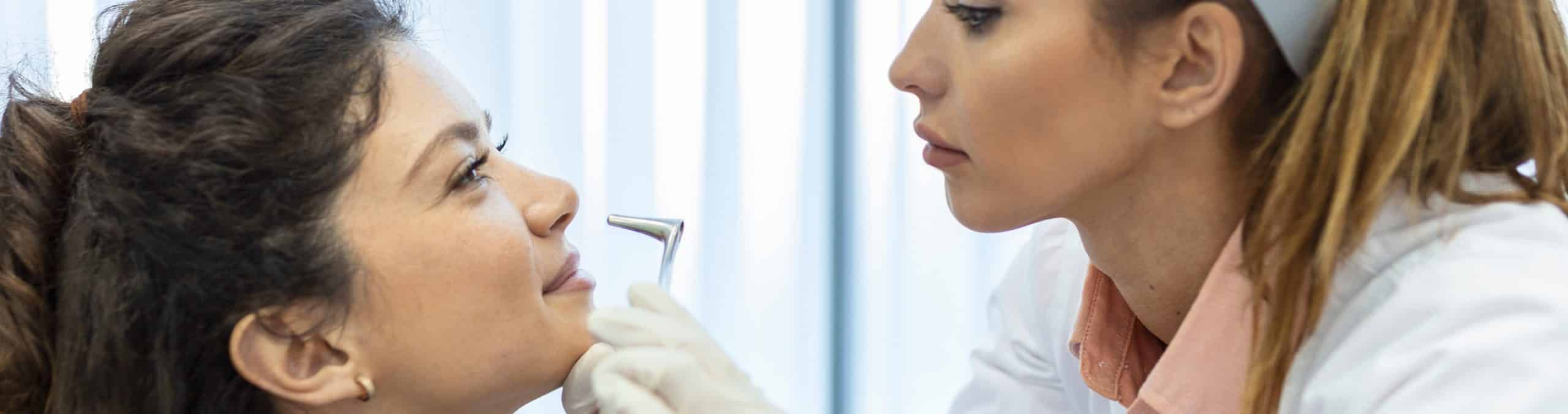 Doctor otorhinolaryngologist checking nose with otoscope patient hospital nasal congestion sinusitis allergy concept 2