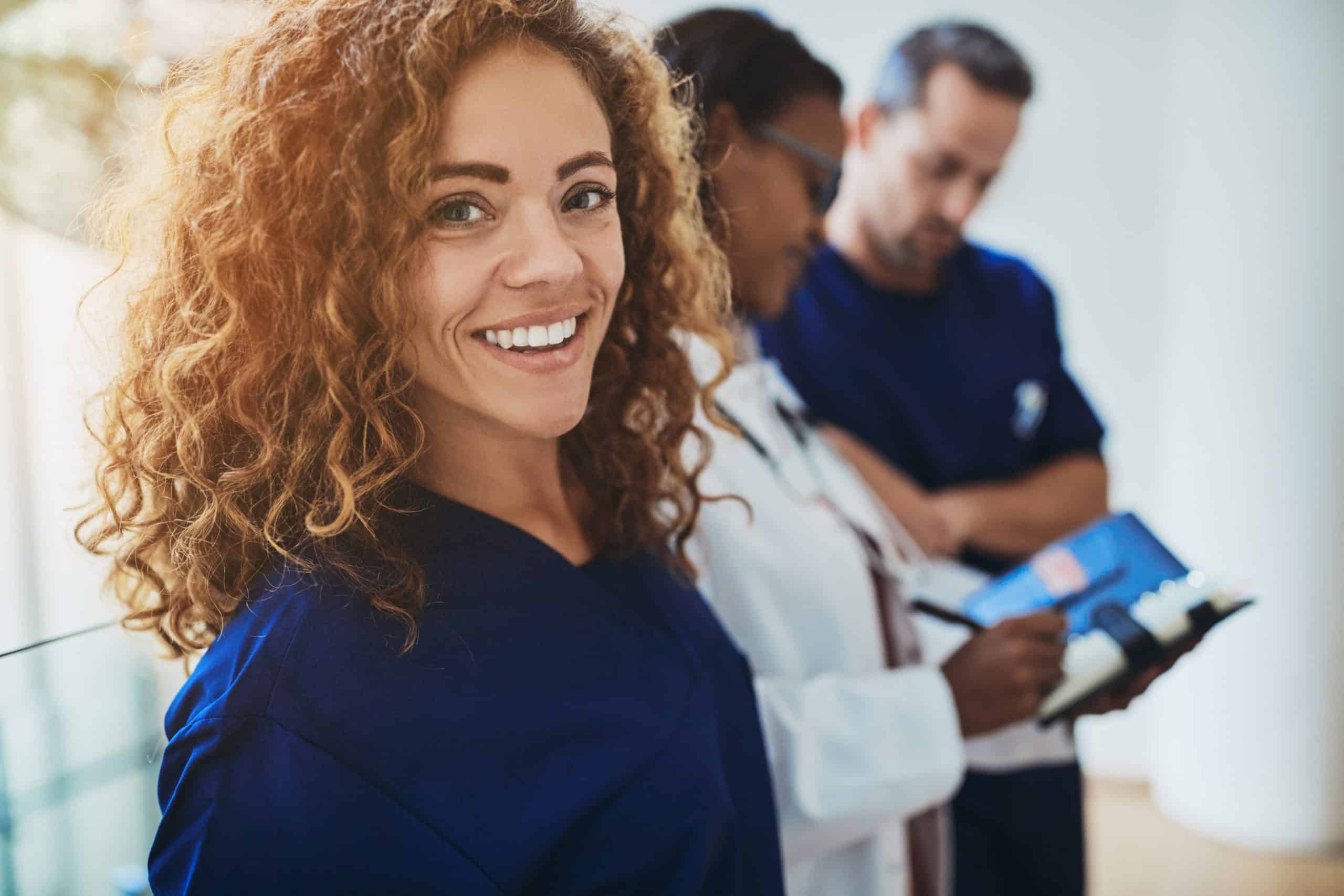 Smiling clinician with colleagues in a hospital corridor