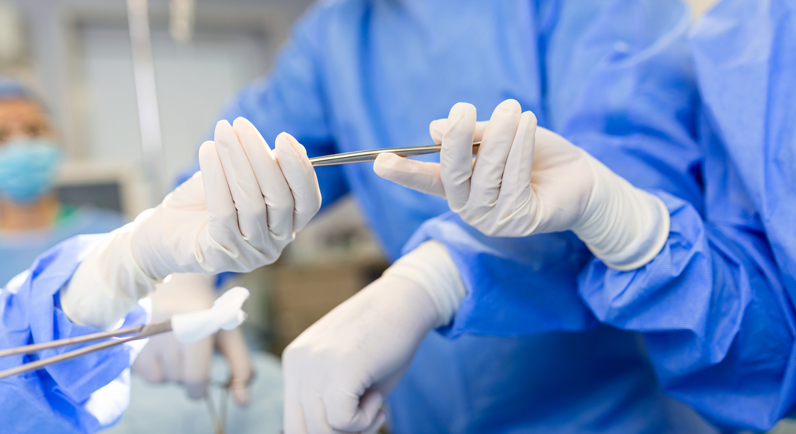 Low angle shot operating room assistant hands out instruments surgeons operation surgeons perform operation…